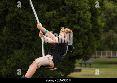 Il bambino oscilla su un'oscillazione in posizione seduta Foto Stock