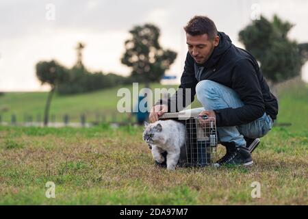 Uomo che cammina fuori con il suo gatto domestico. Cat ama camminare all'aperto Foto Stock