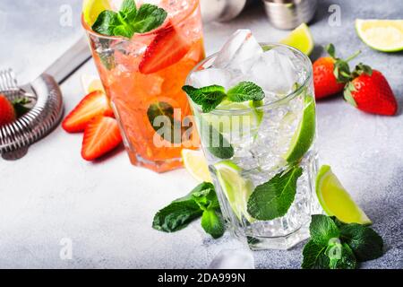 Set di mocktail Mojito fresco con lime, menta, fragola e ghiaccio in vetro su sfondo grigio. Bevande alcoliche o analcoliche fredde, bevande e cockt Foto Stock