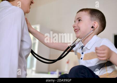 Il bambino è all'appuntamento pediatra. Ascolta uno stetoscopio Foto Stock