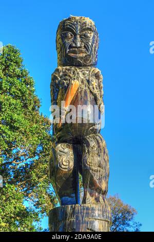 Una scultura Maori a Gate Pa, Tauranga, Nuova Zelanda, raffigurante il profeta Hakaraia Mahika che tiene un club e la Bibbia Foto Stock