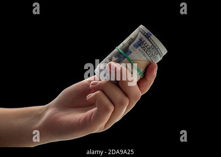 Twisted 100 dollari fatture in mano su uno sfondo nero. Foto Stock