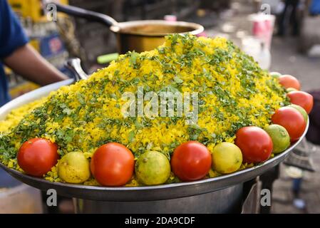 Uomo indiano che vende cibo di strada POHA o pohe di cipolla popolare cibo indiano tradizionale prima colazione piatto, snack fatto con fiocchi di riso / riso battuto. Foto Stock