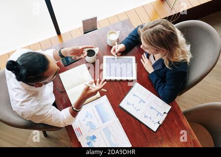 Gli uomini d'affari analizzano i vari rapporti, grafici e diagrammi quando hanno riunione in caffetteria, vista dall'alto Foto Stock