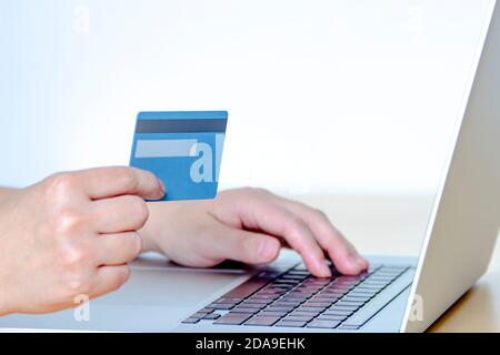 Una persona che acquista online con una carta di credito e un computer portatile. Foto Stock