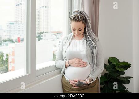 Ritratto di felice giovane donna caucasica con i Dreadlock godendo di lei gravidanza Foto Stock