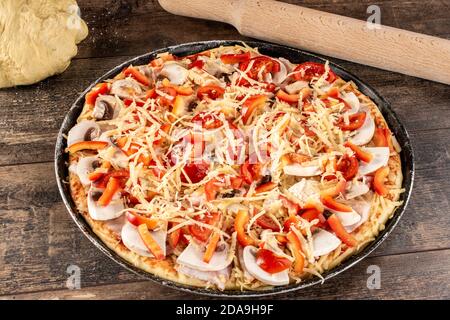 Preparazione della pizza fatta in casa al formaggio non cotto con spilla e pasta. Pizza preparata per essere messa in forno Foto Stock