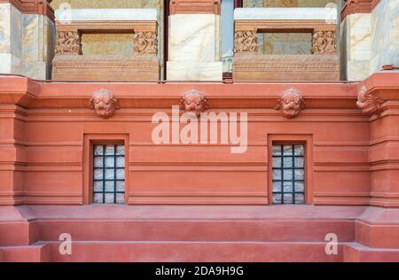 Due finestre adiacenti in ferro battuto a griglia installate nella parete ornamentale all'esterno di un vecchio edificio in pietra con balaustra decorata sul balcone Foto Stock