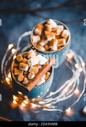 Cioccolata calda con marshmallows e cannella in tazze blu di ceramica su un tavolo. Il concetto di vacanze accoglienti e Capodanno. Foto Stock