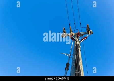 linee elettriche e collegamenti su palo di legno. pali elettrici di legno contro cielo blu. Linee elettriche e fili con cielo blu. Foto Stock