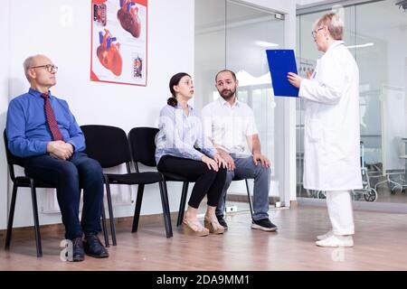 Donna che piange guardando il medico dopo notizie sfavorevoli in zona di attesa ospedale. Ha sottolineato l'uomo e la donna durante l'appuntamento medico. Uomo che lascia la clinica. Foto Stock