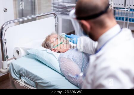Paziente che respira pesantemente senza maschera di ossigeno nella stanza di emergenza dell'ospedale. Medico che aiuta la vecchia donna con malattia polmonare. Medicina medica sistema sanitario epidemico polmoni infezione trattamento Foto Stock