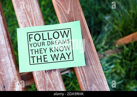 Segui i tuoi sogni conoscono il modo ispirato vita citazione testo scritto su carta su una panchina in un giardino. Foto Stock