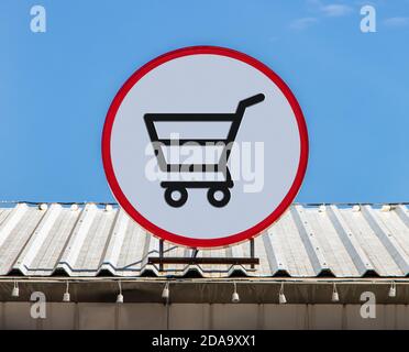 Un cartellone circolare con icona mostra i carrelli per la spesa dal supermercato, è installato su un tetto. Foto Stock
