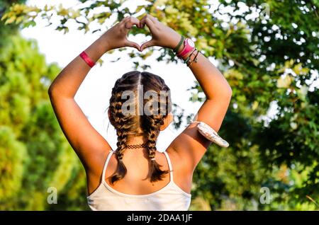 Primo piano di giovane donna in capelli intrecciati con mani a forma di cuore Foto Stock