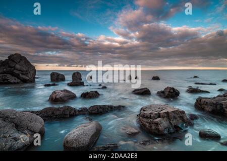 Lunga esposizione del mare e rocce a nero chiesa roccia Devon Foto Stock