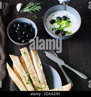 crema d'oliva fatta in casa con una ciotola di olive nere e pane naan fatto in casa, l'olio d'oliva viene versato Foto Stock