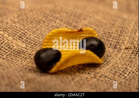 Patatine croccanti con olive su un panno di casa grossolano. Primo piano Foto Stock