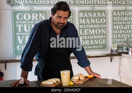 Un cuoco affascinante che presenta la creazione di nuovi piatti in un piccolo ristorante a Lisbona. Gioioso proprietario del ristorante che mostra i nuovi piatti Empanada e il Portug Foto Stock