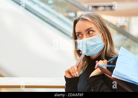 Donna come cliente con maschera facciale e carta di credito mentre fai shopping nel centro commerciale Foto Stock