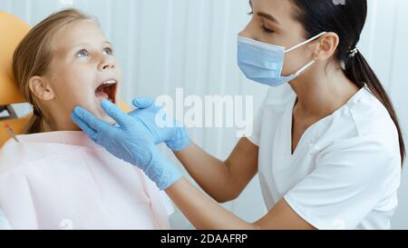 Paziente di sesso femminile seduto sulla poltrona del dentista il dentista  tiene in mano uno specchietto dentale esaminerà i denti del paziente  trattamento dentale professionale