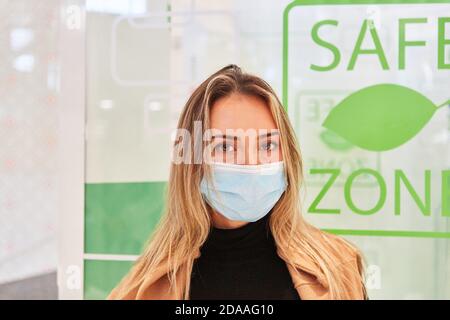 Giovane donna passerby con maschera facciale a causa della pandemia di Covid-19 durante lo shopping Foto Stock