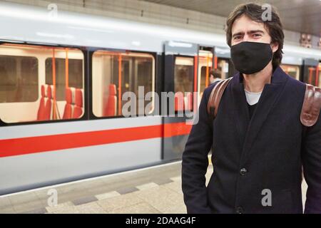 Uomo come pendolari o passeggeri con maschera facciale A causa di Covid-19 è in attesa per la metropolitana Foto Stock