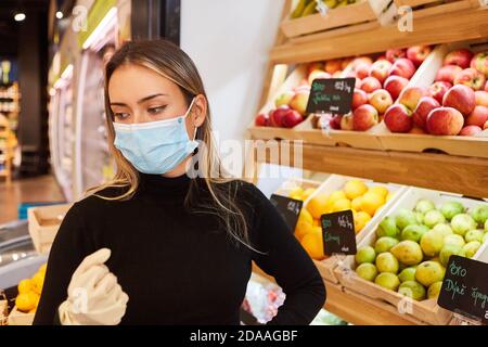 Cliente con maschera facciale a causa della pandemia di Covid-19 durante lo shopping nel supermercato Foto Stock