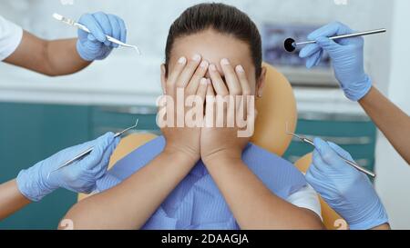 Medici multirazziali in guanti di gomma spaventare la ragazza con strumenti medici Foto Stock