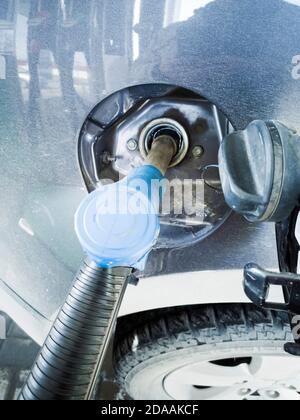 L'auto al distributore di benzina è piena di carburante. Chiudere la pistola di rifornimento nel collo del serbatoio. Foto Stock