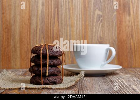 Pila di biscotti al cioccolato e tazza di caffè su un tavolo di legno. Vista frontale. Messa a fuoco superficiale. Foto Stock