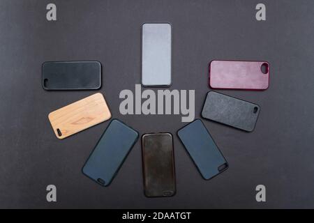 Pila di coperture posteriori in plastica multicolore per telefono cellulare su sfondo nero. Scelta di accessori per la protezione dello smartphone. Un sacco di telefono in silicone Foto Stock