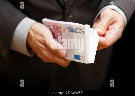 Un uomo conta il denaro in un pacchetto di banconote di 500 euro. Messa a fuoco superficiale. Concetto commerciale o finanziario. Foto Stock