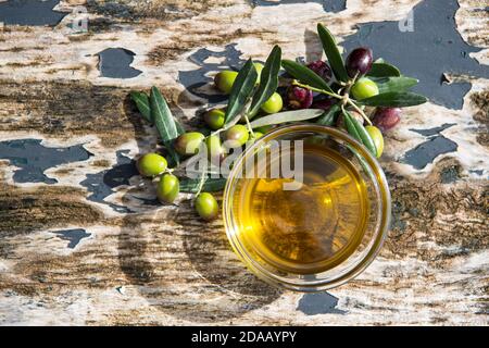 olio extravergine di oliva in ciotole trasparenti di vetro su sfondo ligneo con luci solari. Cibo mediterraneo sano. Foto Stock