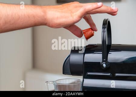 Primo piano di una mano che inserisce una capsula in una macchina da caffè a casa. Concetto di pausa caffè. Foto Stock