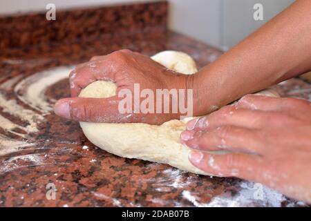 mani che impastano l'impasto per cuocere pane e torte in cucina contatore Foto Stock