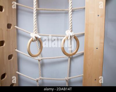 Parete svedese con anelli e parete per l'arrampicata nella stanza dei bambini. Concetto di parenting sano Foto Stock