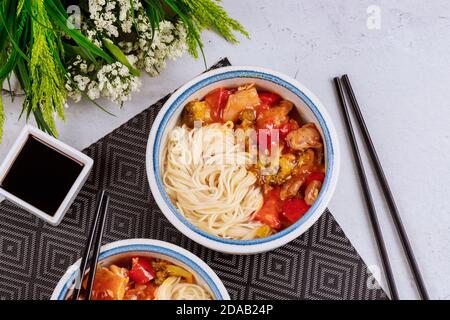 Tagliatelle di riso bollite con broccoli, pollo e peperone in salsa dolce e piccante. Cibo asiatico. Foto Stock