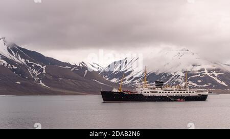 La sig.ra Nordstjernen fa parte della flotta Hurtigruten nel porto di Longyearbyen, Svalbard, Norvegia, con montagne avvolte da nuvole sullo sfondo. . Foto Stock