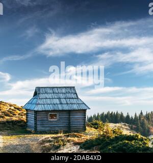 Cabina di montagna in legno e cielo blu. Casa sola sul prato primaverile. Situato luogo: Carpazi, Ucraina, Europa Foto Stock