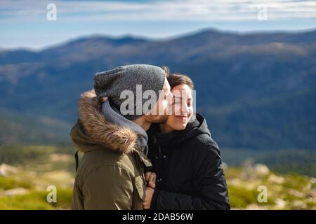 Felice giovane coppia abbraccio e bacio. Giovani che indossano abiti invernali in natura. Foto Stock