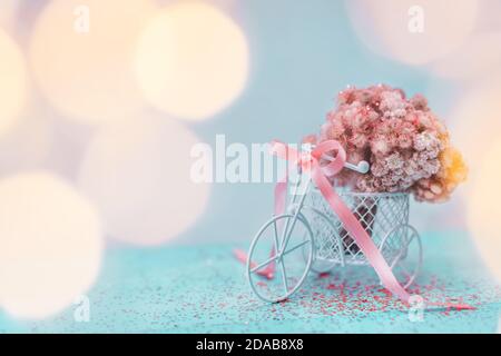 Bicicletta retrò con cesto di fiori rosa su sfondo chiaro. Foto Stock