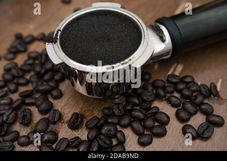 Macine di caffè nel portafiltro della macchina. Fagioli in tutto il posto. Foto Stock