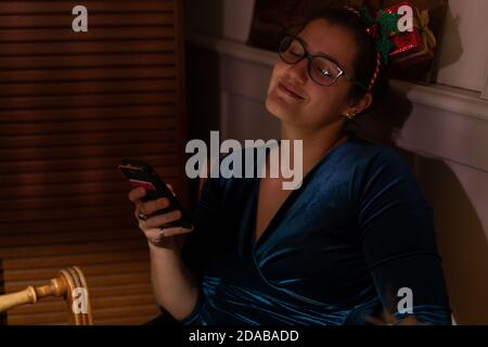 Una giovane donna rilassante si rilassò e ascolterò il suono del suo cellulare a natale. Foto Stock