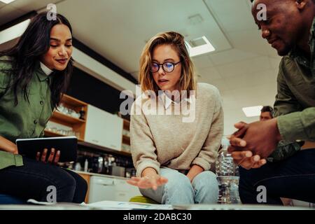 Diversi gruppi di colleghi si riuniscono per trattare la presentazione del progetto sedersi nella sala d'ufficio prima della presentazione Foto Stock
