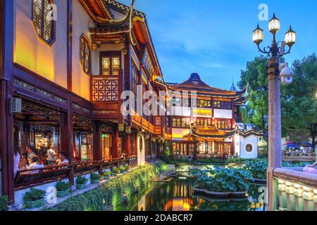 Scena notturna nel famoso Giardino Yu e Bazaar, con ristoranti e negozi di fronte al piccolo stagno centrale a Shanghai, Cina Foto Stock