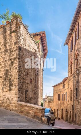 Strada stretta Via Palestro con auto nella città italiana Di San Gimignano Foto Stock