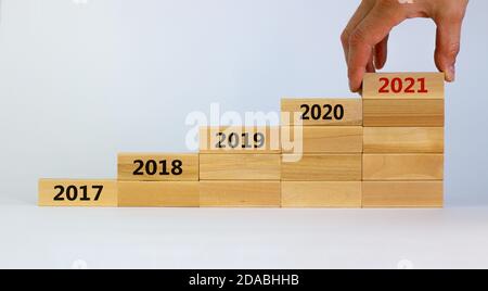 Mano maschio che posiziona un blocchetto con numero '2021' su una torre a blocchi con numeri '2017, 2018, 2019, 2020'. Splendido sfondo bianco. Spazio di copia. Affari Foto Stock