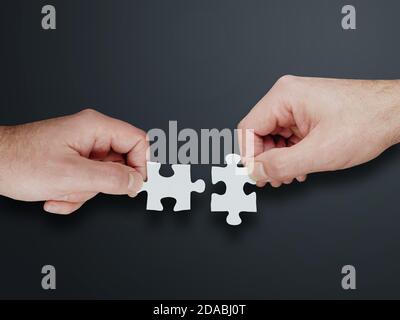 mani di due persone che riuniscono due pezzi di puzzle, trovando soluzioni e concetto di lavoro di squadra Foto Stock