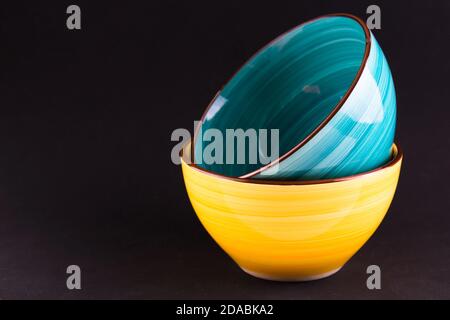Due ciotole in ceramica gialla e blu su sfondo nero.spazio copia. Foto Stock